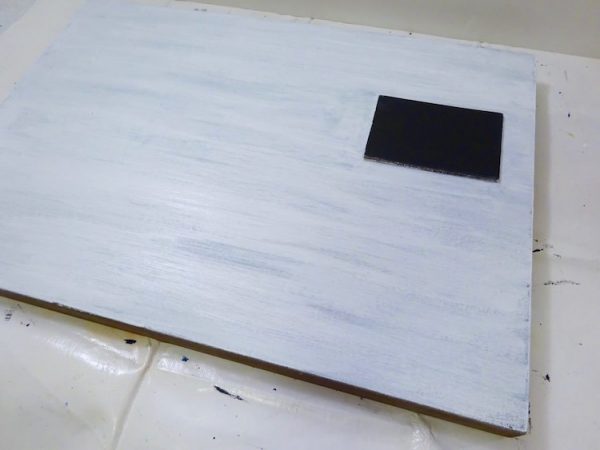 painted white sign with black square prominent
