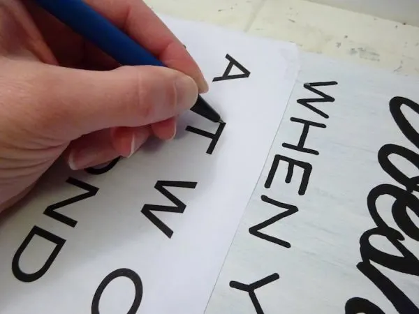tracing a template with a pen onto a sign