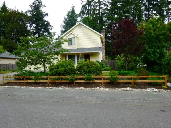 Two rail wood fence in front of a house