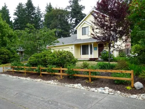 Two rail wood fence in a garden in front of a house