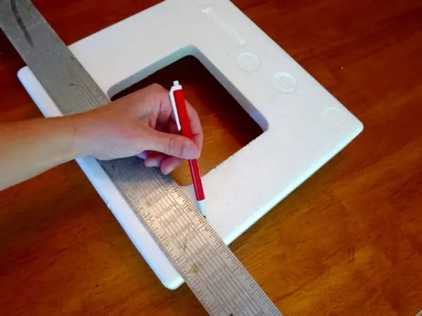 Marking a cutting line on a styrofoam block to be made into a display shelf