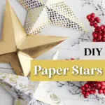 Three folded paper stars made of gold, white with gold dots, and white with black floral print paper. Red berries are scattered nearby. The text reads "DIY Paper Stars" and "SingleGirlsDIY.com.