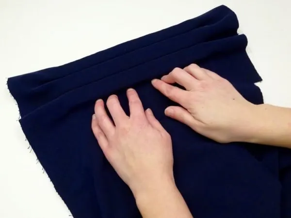 pushing blue velvet fabric onto foam rolls to make a jewelry display