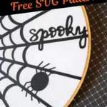 Embroidery hoop featuring a black spider web and the word "spooky" on a white fabric background. Text overlay reads, "DIY Halloween Decor Free SVG Pattern.