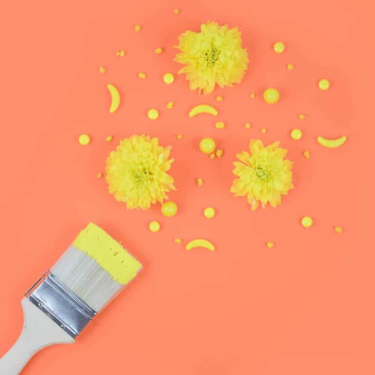 paintbrush with yellow paint against orange background