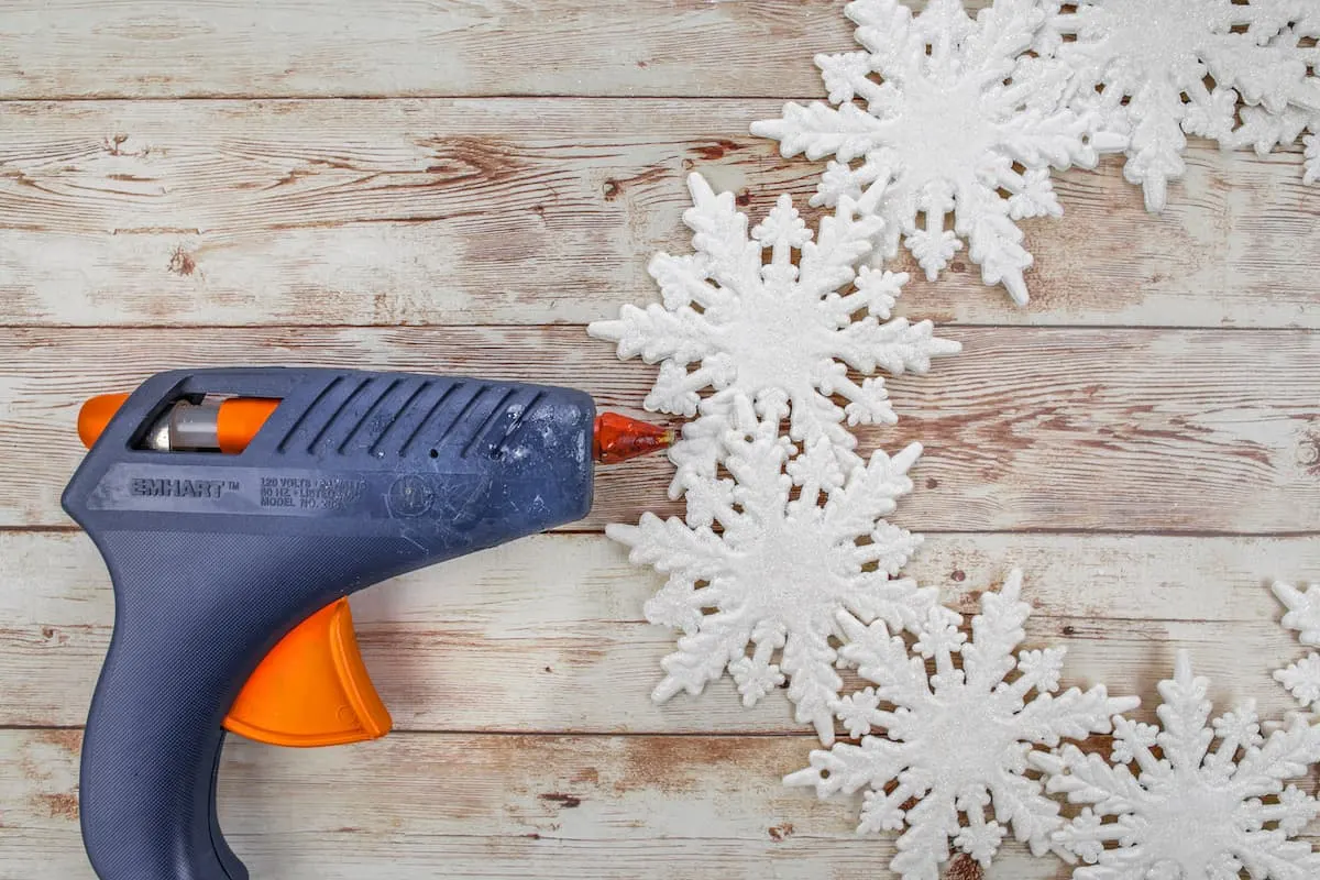hot glue gun and snowflake ornaments on wooden table