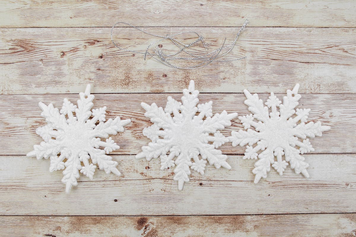 three white snowflake ornaments on wooden background