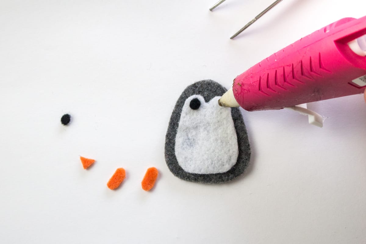 Hot glueing felt eyes on penguin craft