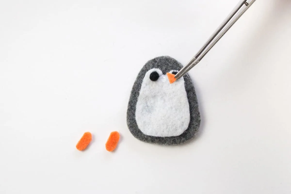 Placing nose on felt penguin with tweezer