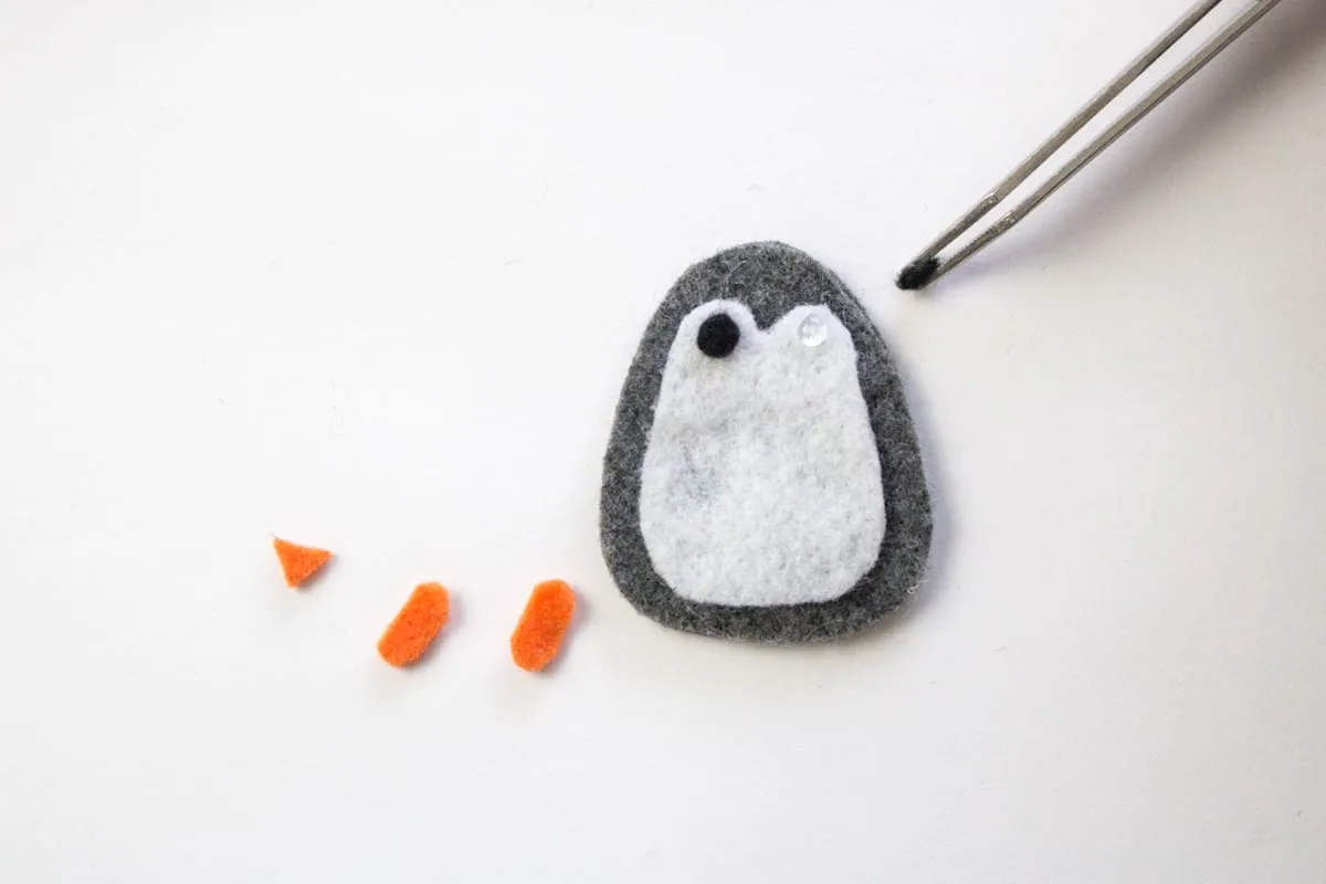 Using tweezer to place felt eye on penguin ornament