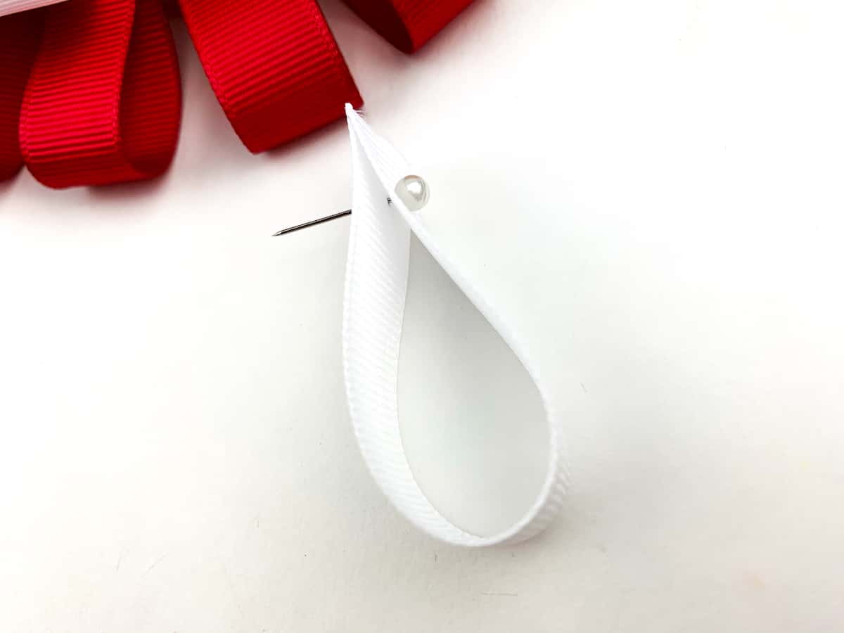 white ribbon in a loop with a pin through it