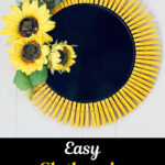 A black pizza pan base is bordered with yellow clothespins and decorated with three artificial sunflowers and green leaves on the left side, creating a cheerful sunflower clothespin wreath. Text reads &ldquo;Easy Clothespin Sunflower Wreath.&rdquo;.