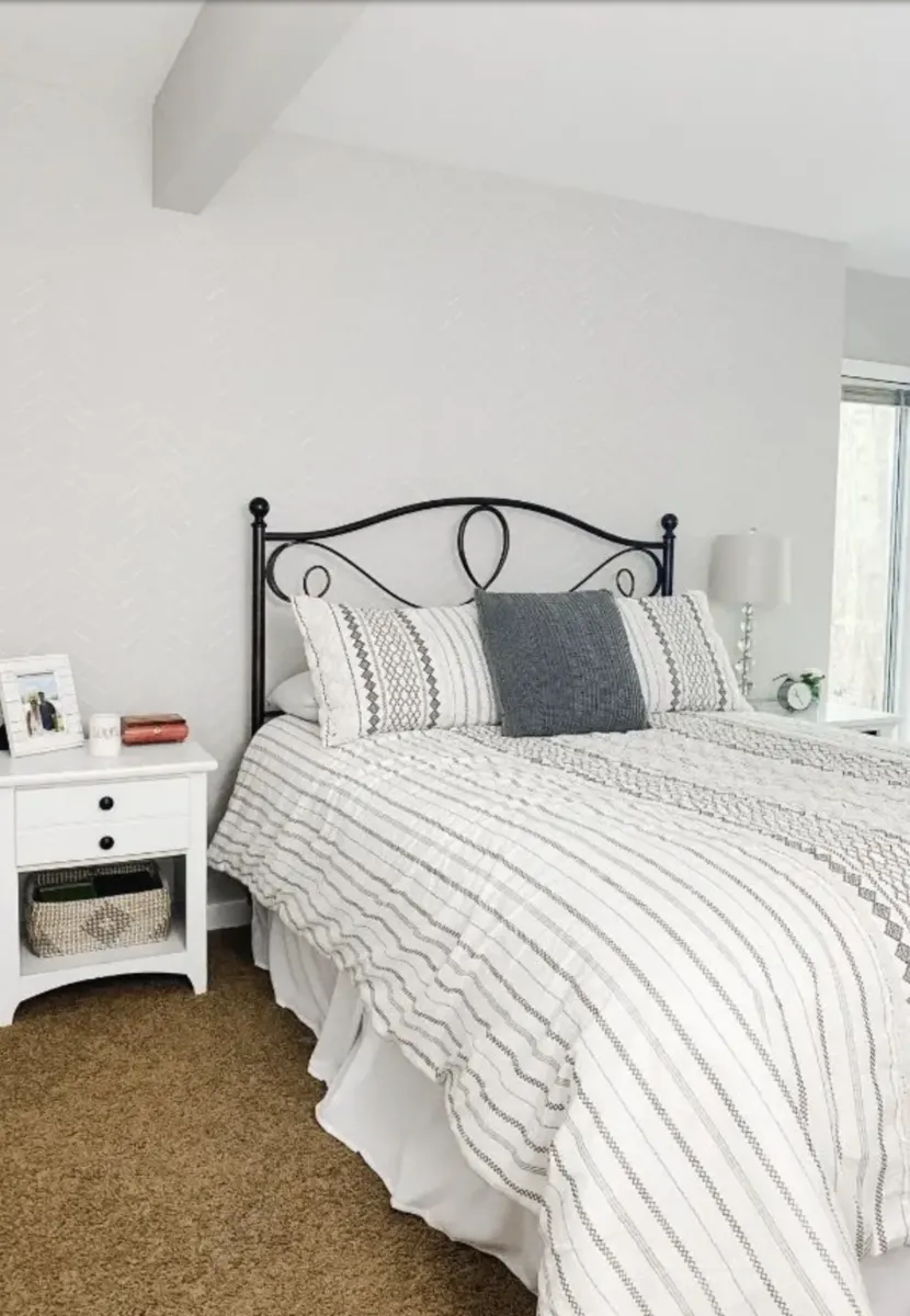white walls in bedroom with grey and white striped bedspread on bed