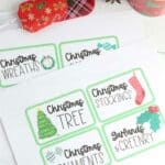 Christmas decoration organizing labels on table next to roll of ribbon and greenery