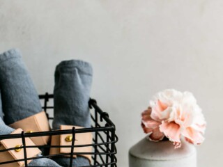 black wire basket filled with rolled napkins and a pink flower in a vase nearby