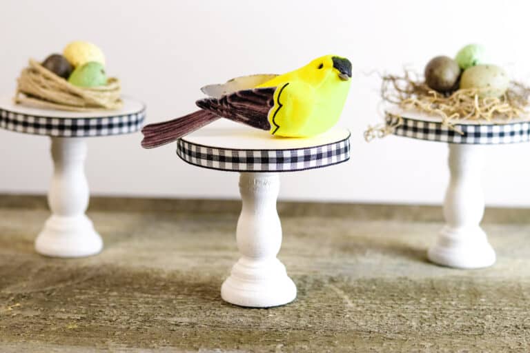 three diy wooden pedestals made out of candlesticks with bird themed decor on top of the stands