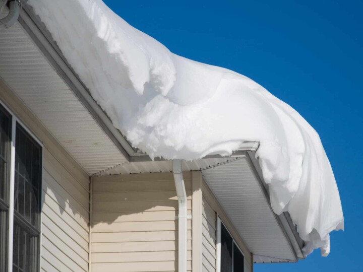 layers of snow on gutters of roof of house