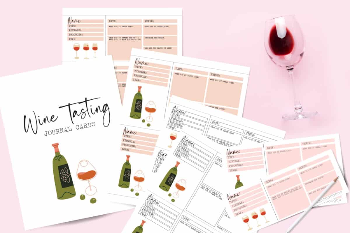 wine tasting note cards on pink background with glass of wine