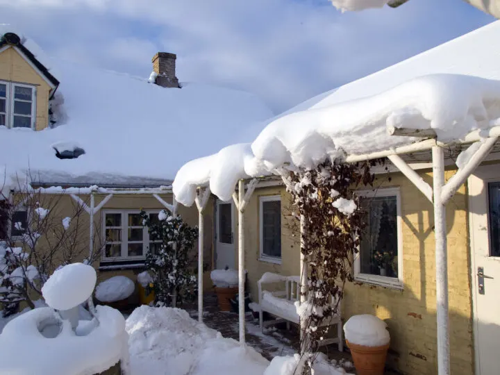 heavy snowfall on top of roof of house