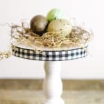 mini wooden pedestal with gingham check edge and birds nest on top of base