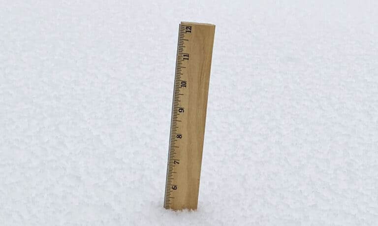 A wooden ruler sticking out of the snow