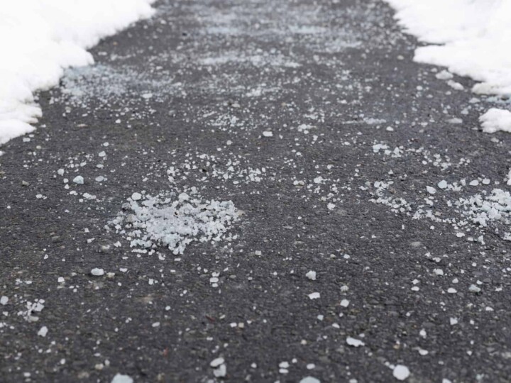 rock salt on black driveway surrounded by snow