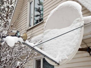Satellite antenna dish covered with snow on a roof