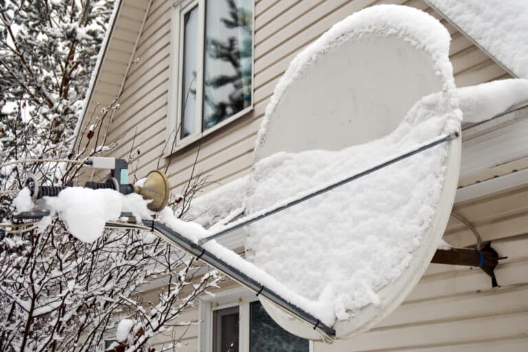 Satellite antenna dish covered with snow on a roof