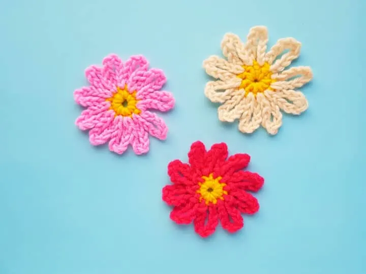 three pretty crocheted flowers in shades of pink, white and red