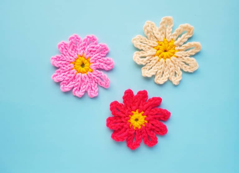 three pretty crocheted flowers in shades of pink, white and red