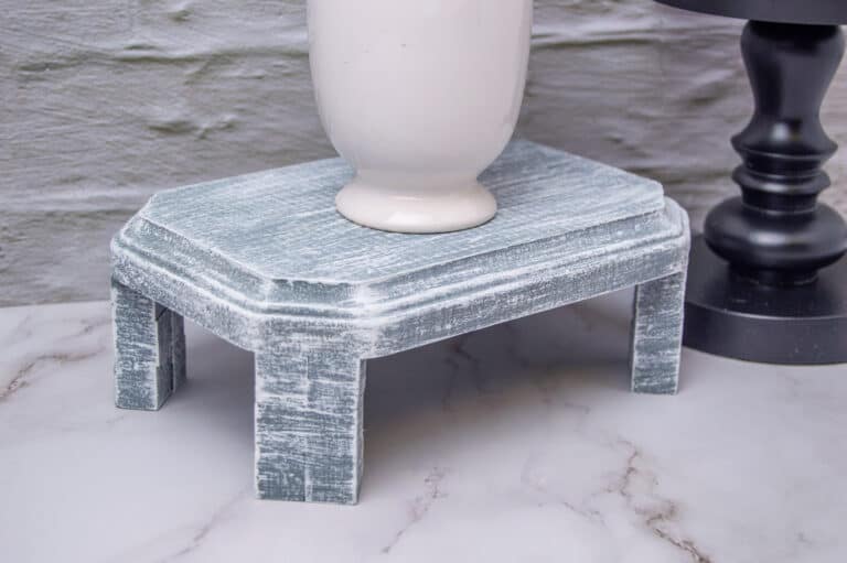 white vase on a gray wooden display pedestal