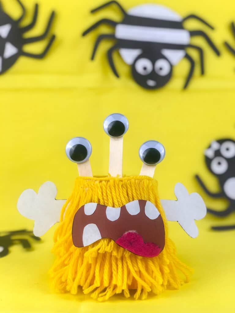 halloween paper cup monster with three eyes against a yellow background