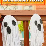 two cute mop head ghosts hanging from porch railing
