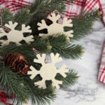wooden snowflake cutouts laying with Christmas tree branch and red and white fabric background