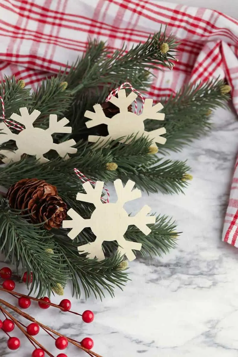 wooden snowflake cutouts laying with Christmas tree branch and red and white fabric background