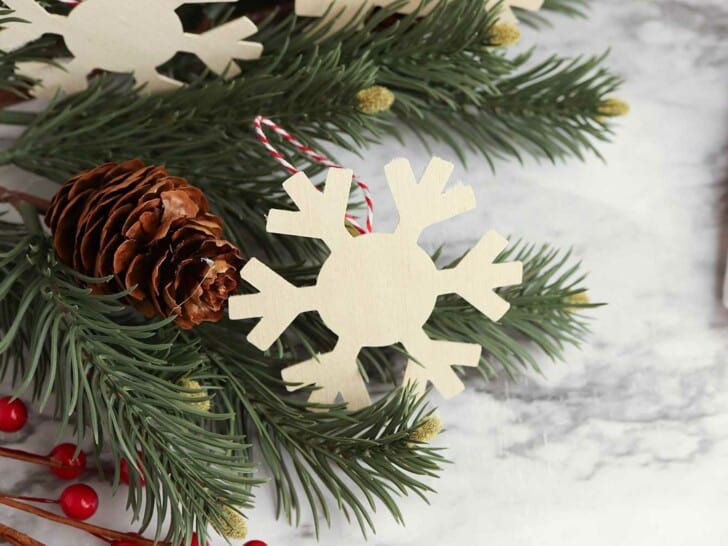 wooden snowflake cutout in Christmas tree with pinecone and red berries