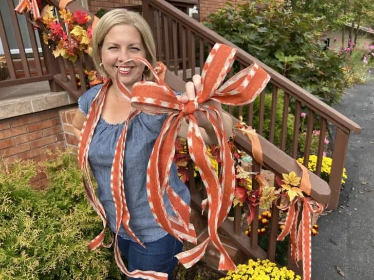 woman holding a handmade bow in front of her with decorated porch in background