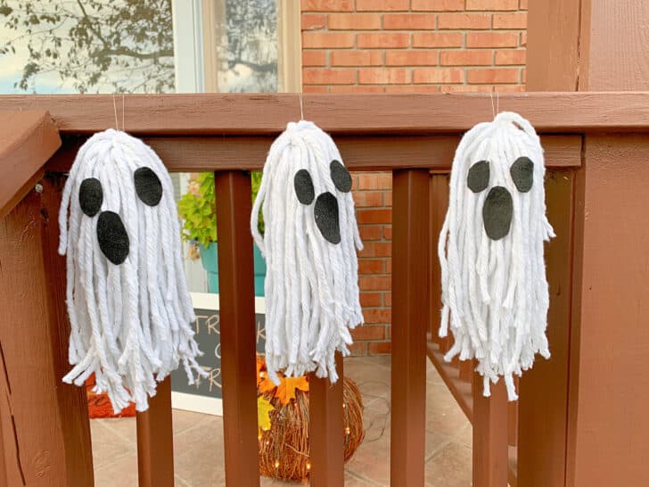 three mop head ghosts hanging from porch railing