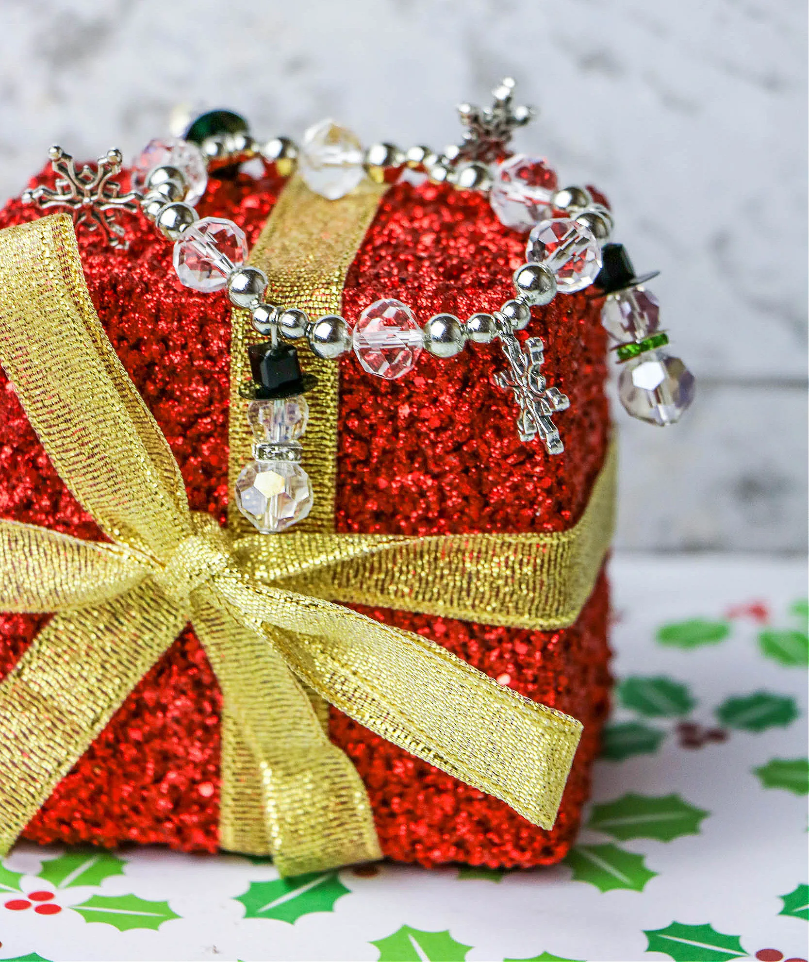 doy snowman bracelet made from beads and charms displayed on sparkly red miniature present