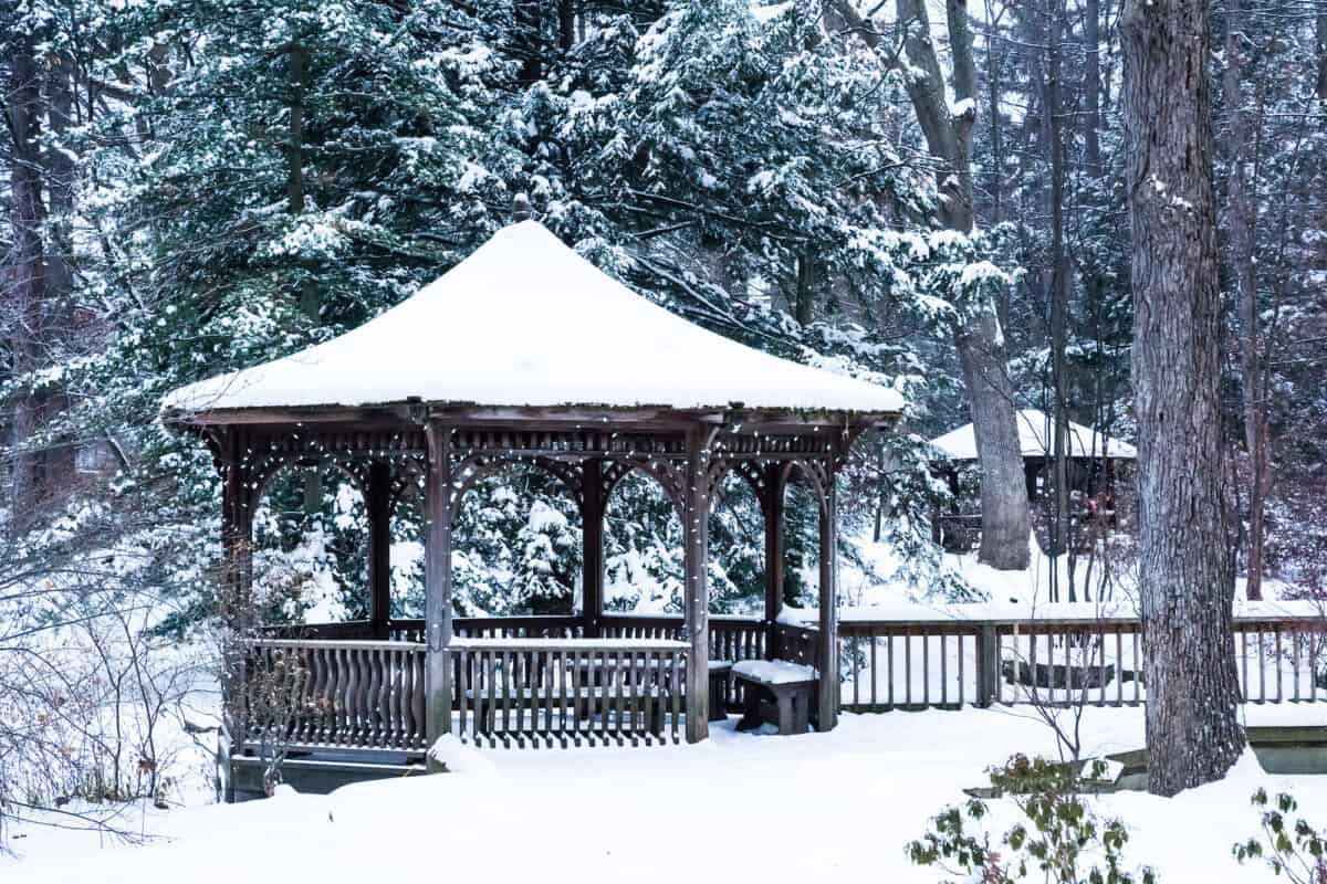 snow on a wooden gazebo in the forest