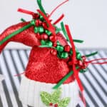 diy jingle bell bracelet on top of Santa hat ornament against striped background