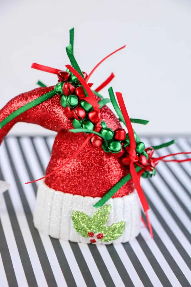 diy jingle bell bracelet on top of Santa hat ornament against striped background