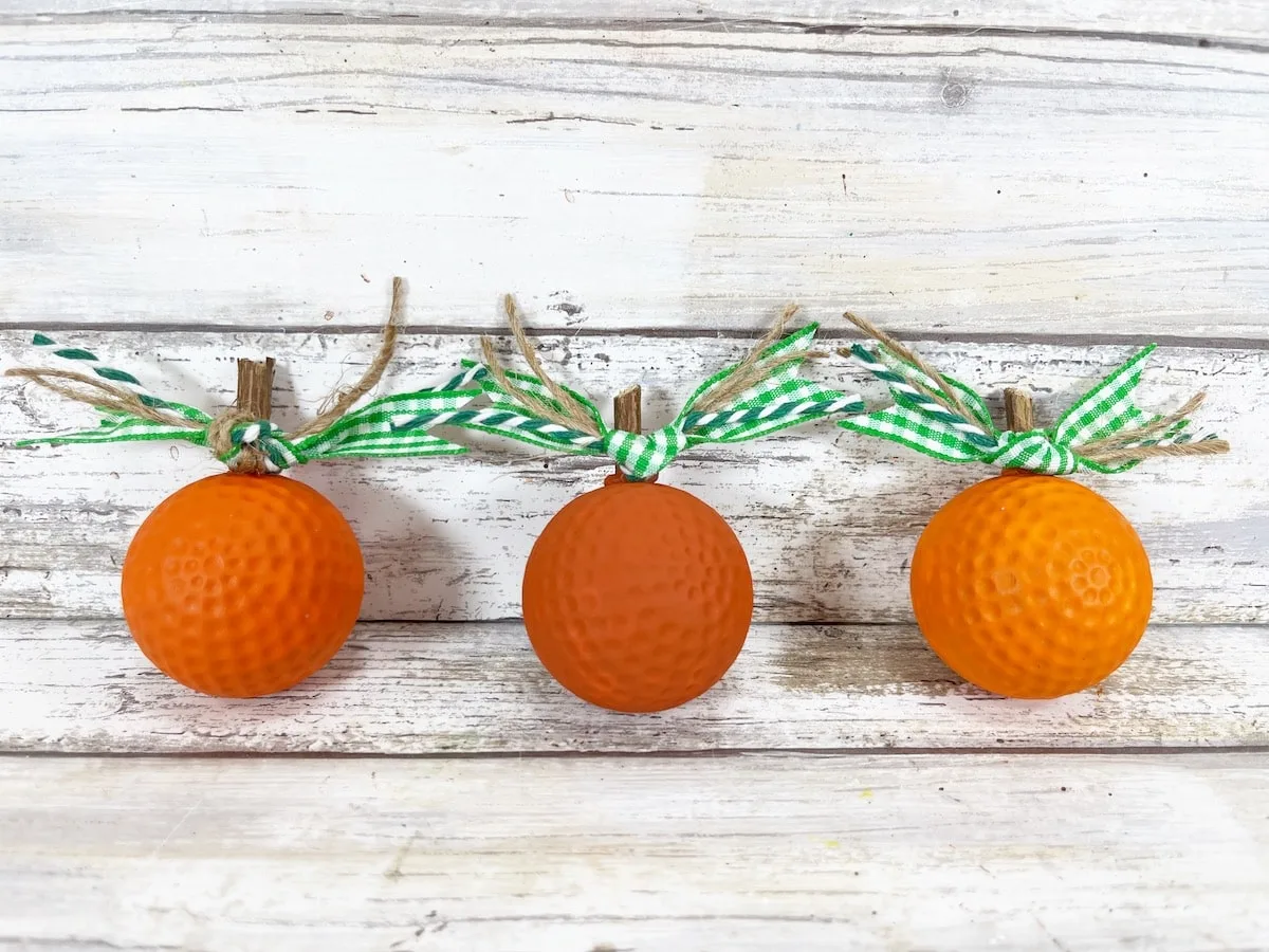 three Golf Ball Pumpkins laying on a wood background