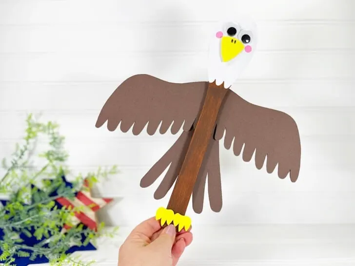 Wooden Spoon Bald Eagle Craft In Hand against white wood beyond