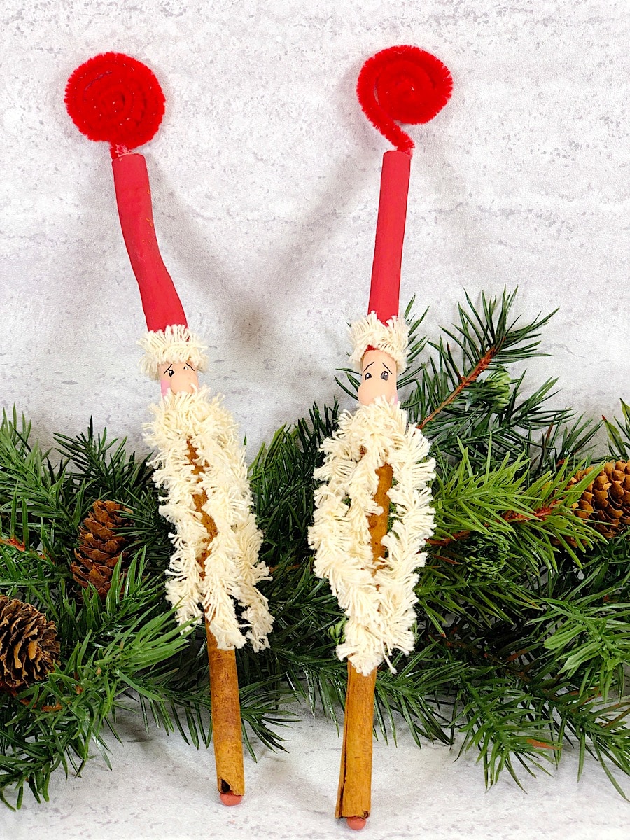 Cinnamon Stick Santa Ornament Against Green Pine and Pinecones