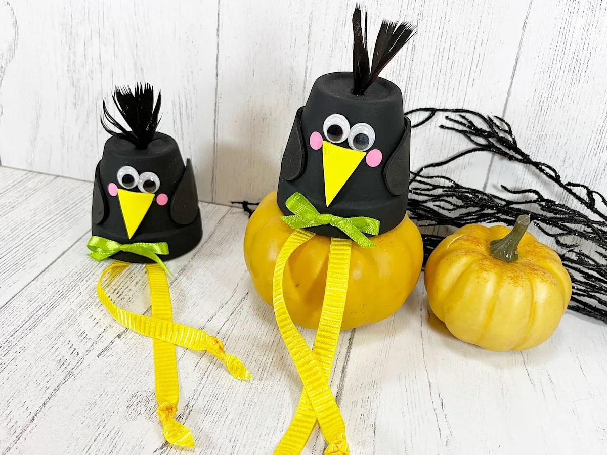 Clay Pot Crows With Pumpkins Against White Wood Wall