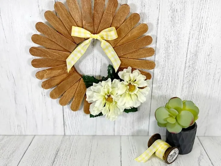Craft Stick Wreath Hanging on White Wood Wall