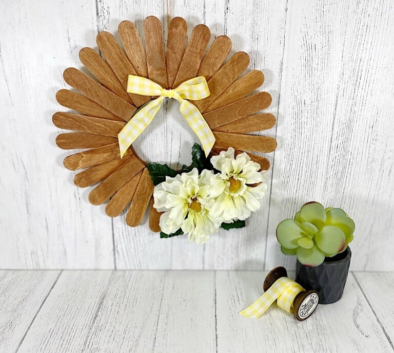 Craft Stick Wreath Hanging on White Wood Wall