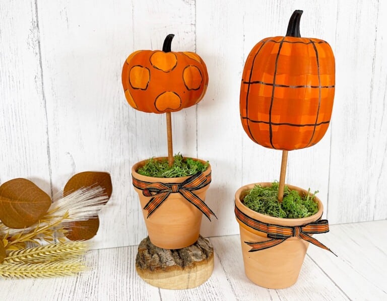 Dollar Tree Pumpkin Topiary Against White Back With Fall Leaves