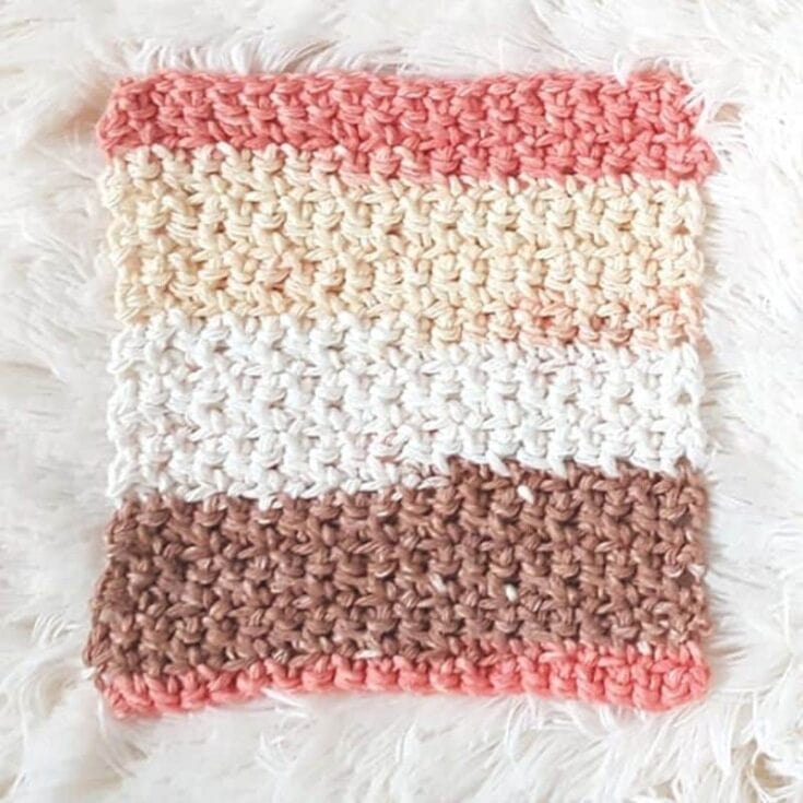 A crocheted dishcloth on a white fur rug.